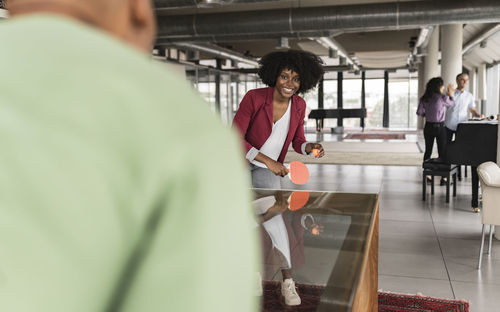 Happy businesswoman playing table tennis with colleague in office