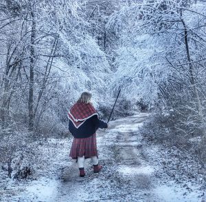 Rear view of person walking on snow covered landscape