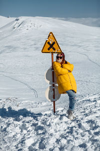 A young woman stands unhappily at the prohibition sign