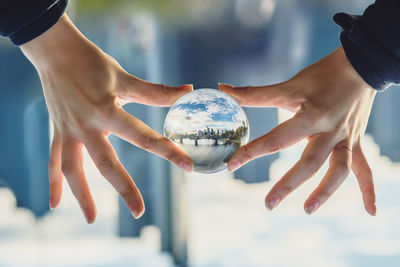 Cropped hands holding crystal ball with reflection