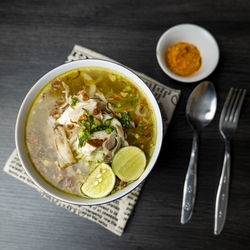 Soto ayam, indonesian food, photographed high angle view decorated with cutlery