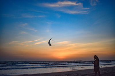 Silhouette person on beach against sky during sunset