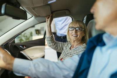 Senior couple trying out car in car dealership