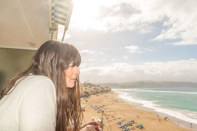 Young woman on beach against sky