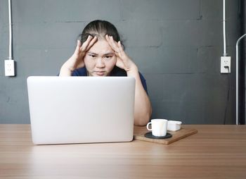 Young woman using phone while sitting on table