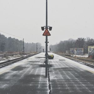 Road by railroad tracks against sky during winter