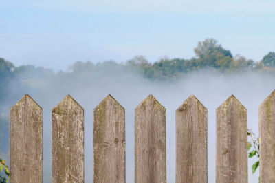 Wall of fog behind a wooden fence on an autumn day