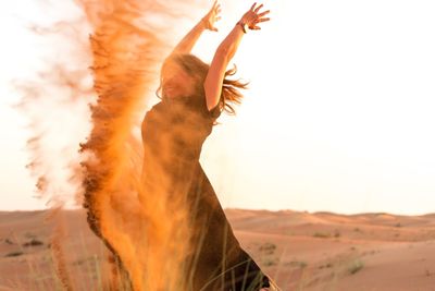 Portrait of young woman standing in desert against clear sky