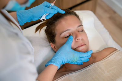 Midsection of doctor examining patient lying on bed