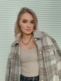 Portrait of beautiful young woman standing against wall