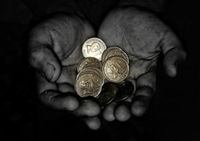 Cropped hands holding coins in darkroom