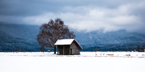 House on snow covered landscape against sky