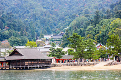 Houses by sea against trees and mountains