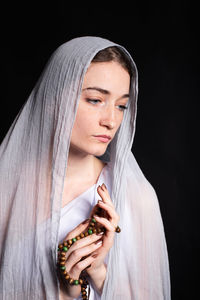 Beautiful young woman in a headscarf on a black background is modest. religion