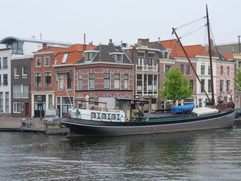 Boats in canal amidst buildings in city against sky