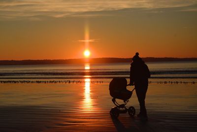 Silhouette man at beach against sky during sunset