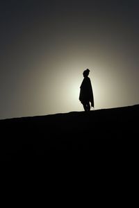 Silhouette woman standing on land against clear sky during sunset
