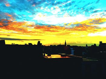 Silhouette cityscape against dramatic sky during sunset