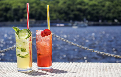 Close-up of lemonades in glasses on pier against sea