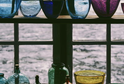 Close-up of glass bottles on window