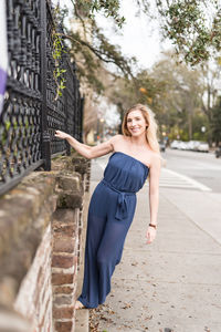 Portrait of smiling young woman holding fence