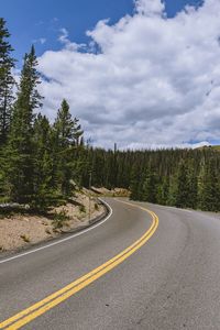 Road by trees against sky