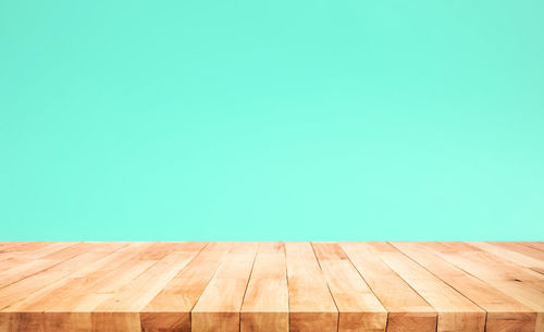 Empty wooden floor against clear blue sky