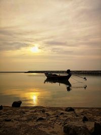 Silhouette boat on beach against sky during sunset