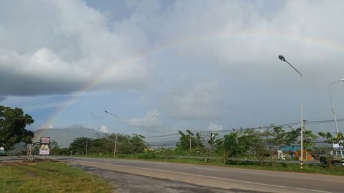 Rainbow over road against sky