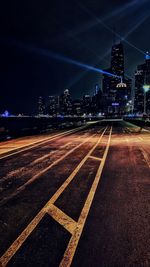 Surface level of road against illuminated buildings in city at night