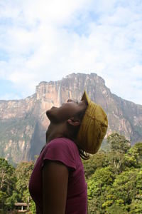 Rear view of woman standing on rock against sky