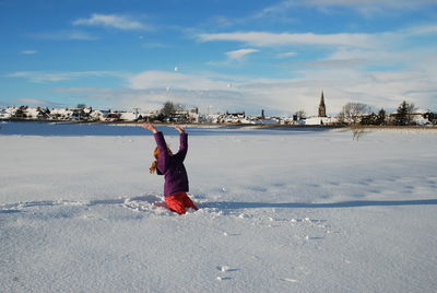 Teenage girl playing with snow against sky