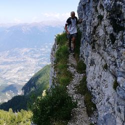 Rear view of men standing on rock against mountains