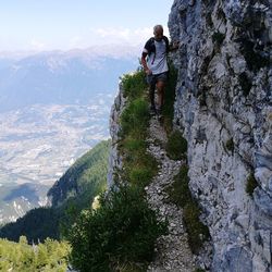 View of men hiking on rock against mountains