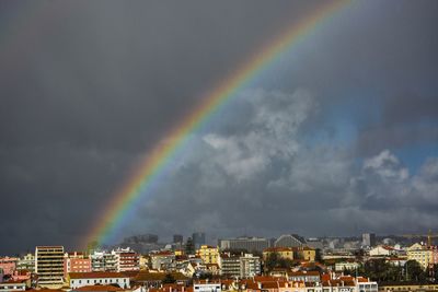 Rainbow over cityscape against sky