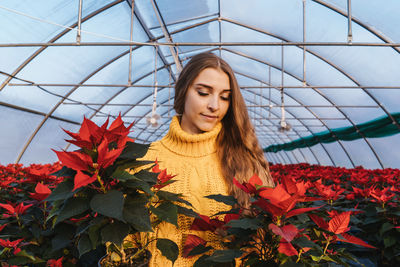 Young woman standing amidst plants in greenhouse