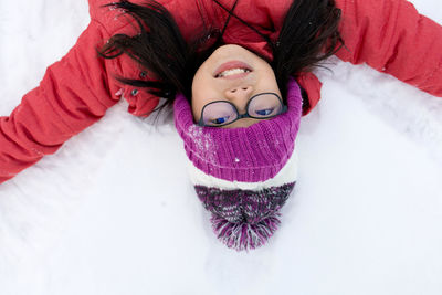 High angle portrait of girl lying on snow