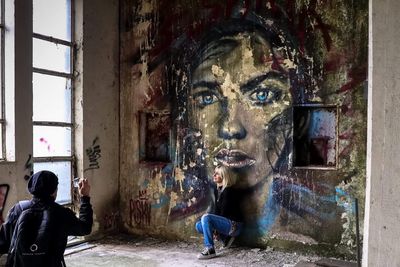 Full length of man and woman looking through window in abandoned building