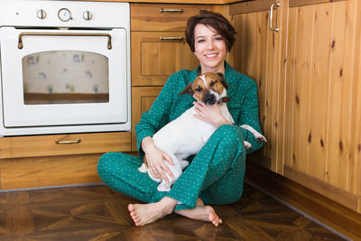 Portrait of smiling woman playing with puppy at home