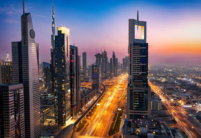 High angle view of light trails on road in modern cityscape at dusk