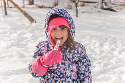 Smiling girl standing on snow during winter