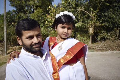 Portrait of father and daughter against trees