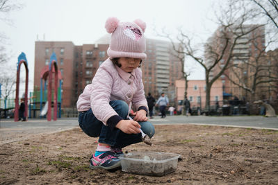 Girl digging in the dirt on the playground on a foggy fall day