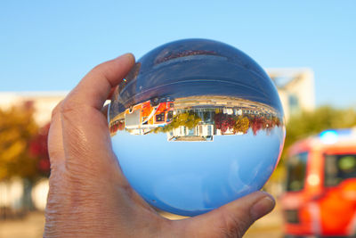 Close-up of hand holding glass against clear blue sky