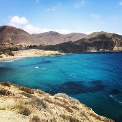 Scenic view of sea and mountains against blue sky