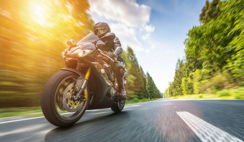 Blurred motion of man riding motorcycle on road