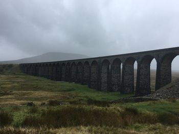 Bridge over field against sky
