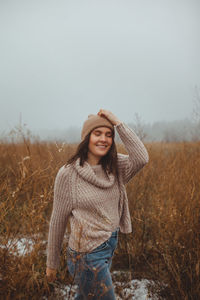 Young woman wearing hat standing on field against sky