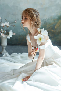 Woman in white dress with flower looking aw