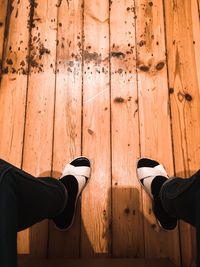 Low section of man standing on wooden floor